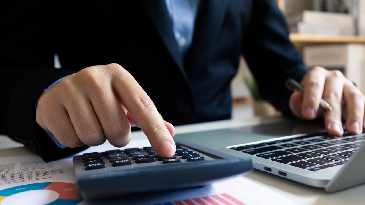 Person working on laptop and calculator, Private AI for the Enterprise | DXC Technology Insights