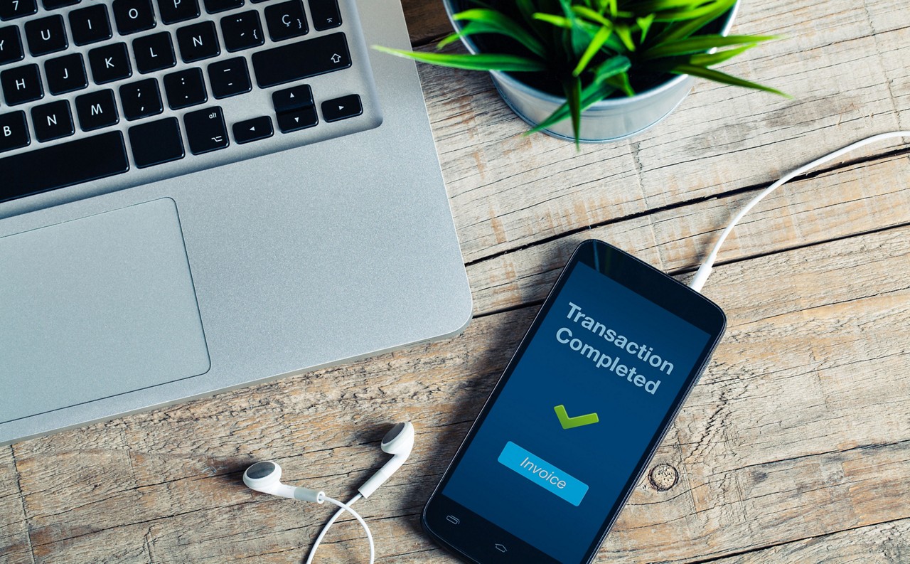 Transaction Completed message on smart phone screen. Detail of workplace.