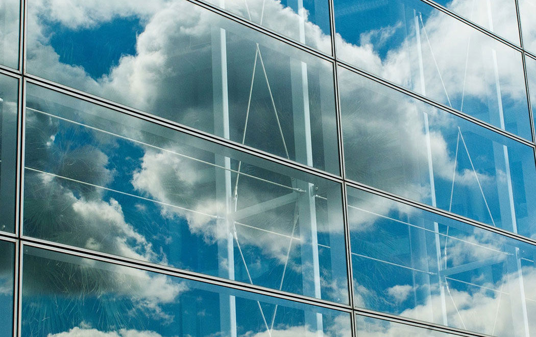 Clouds and blue sky reflected on the glass facade of a modern building, Network CoreEdge, HPE | DXC Technology Partner