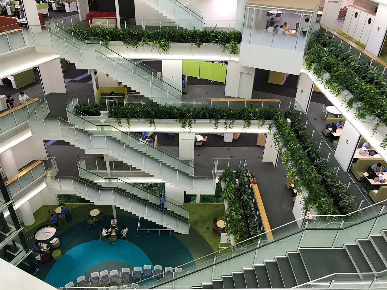 Top-down view of open office space with stairs, plants and furniture, Support Services | DXC Technology Customer Story
