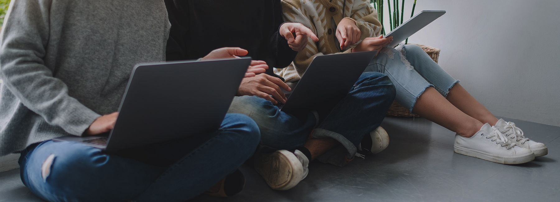 Three workers sitting on floor using laptops, Modern Device Management | DXC Technology