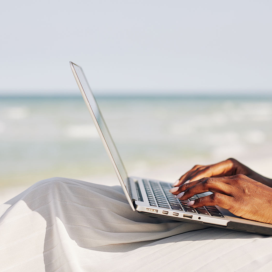 hands typing on keyboard at beach, Modern Workplace | DXC Technology