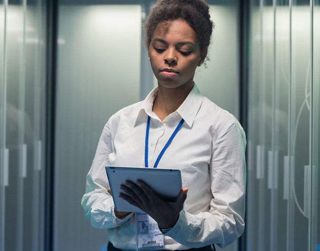 IT worker in a data center checking tablet, Mainframe Services & Solutions | DXC Technology Insights  