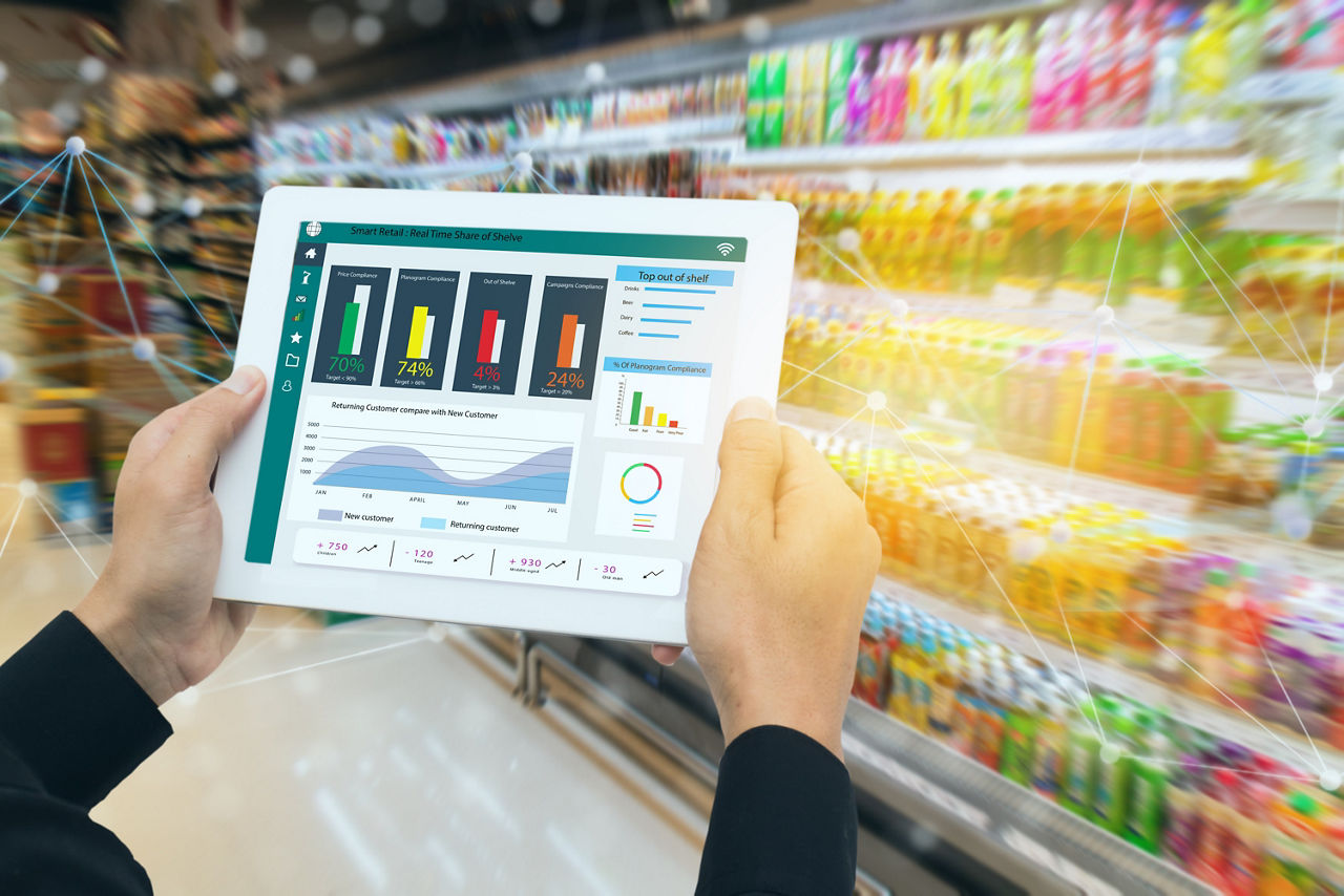 Hands holding tablet in front of products on shelves, merchants using data in retail, Data & AI | DXC Technology Insights