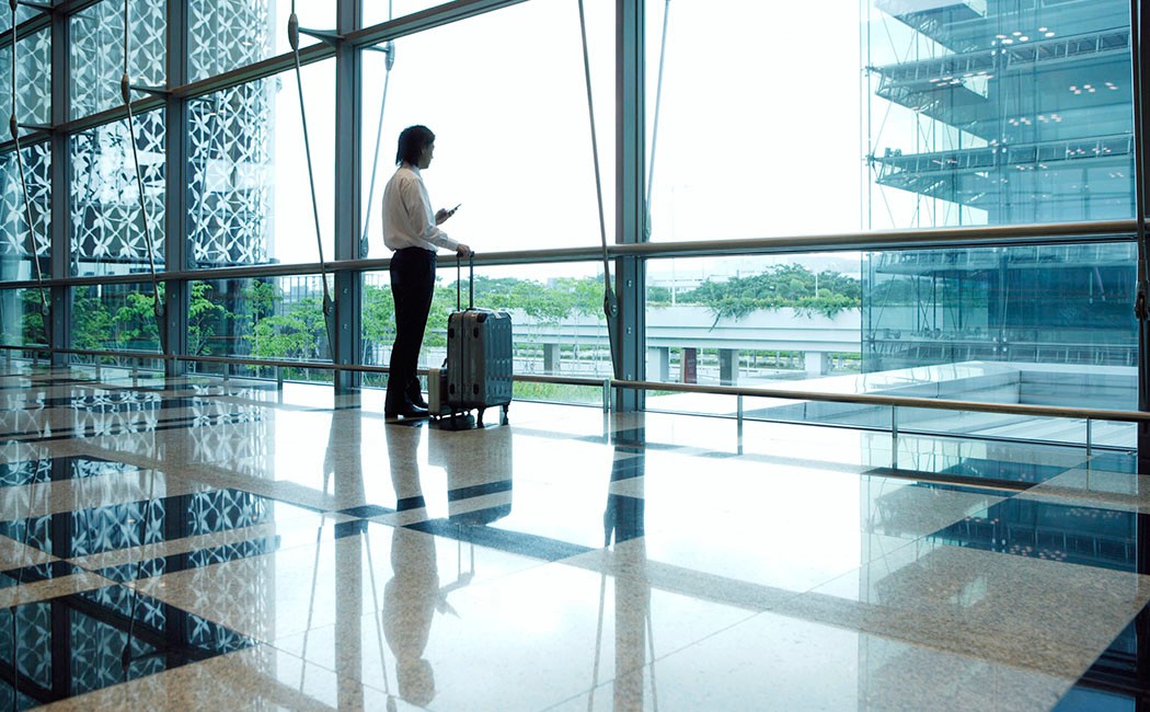 Singapore --- Businessman standing in airport using PDA --- Image by © Ocean/Corbis