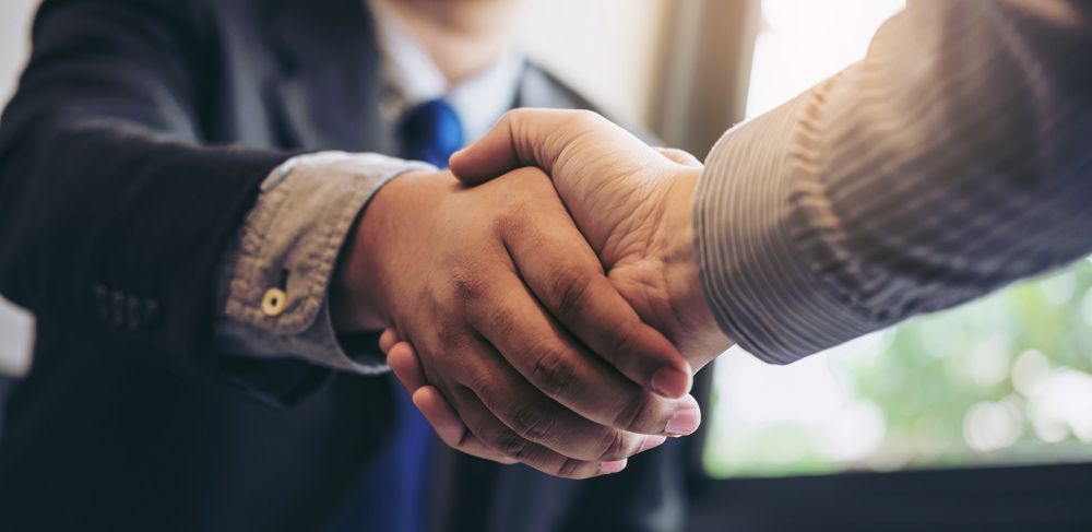 Two people shaking hands in office 