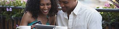 Couple in outdoor café making an ecommerce purchase on a tablet