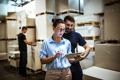 Woman and man in warehouse working on tablet inventory