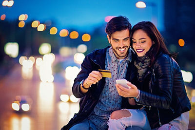 A couple having a fun night while purchasing with their smartphone