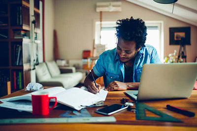 Casually dressed man in his home office writing up his resume