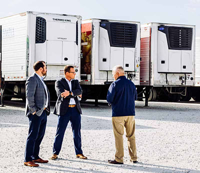 Group of transportation experts in a parking lot with semi trailers