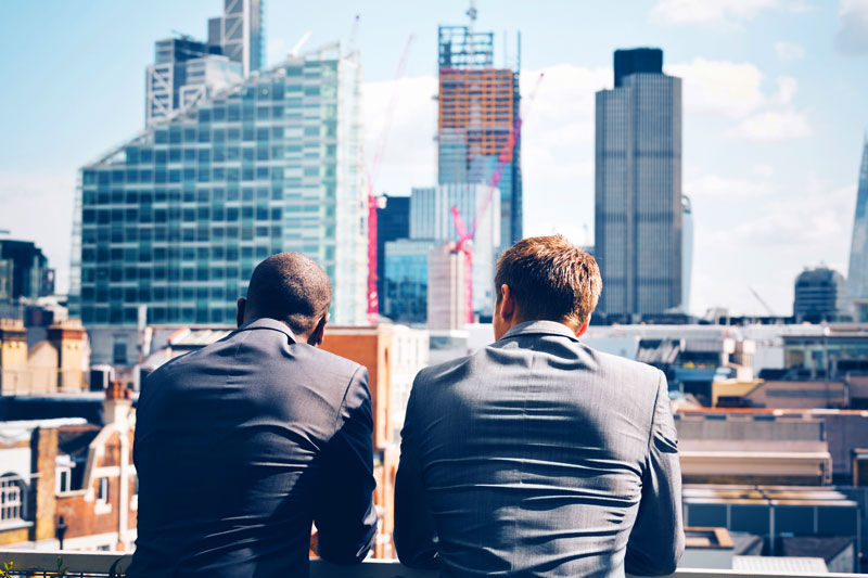Two corporate businessmen looking at over the downtown skyscrapers