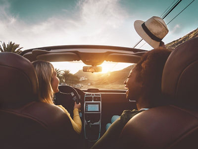 Happy girls doing road trip in tropical city - Travel people having fun driving in trendy convertible car discovering new places - Friendship and youth girlfriends vacation lifestyle concept