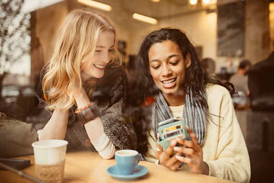 Two girls paying for their coffee with their smart phone