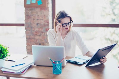 woman with glasses looking at computer