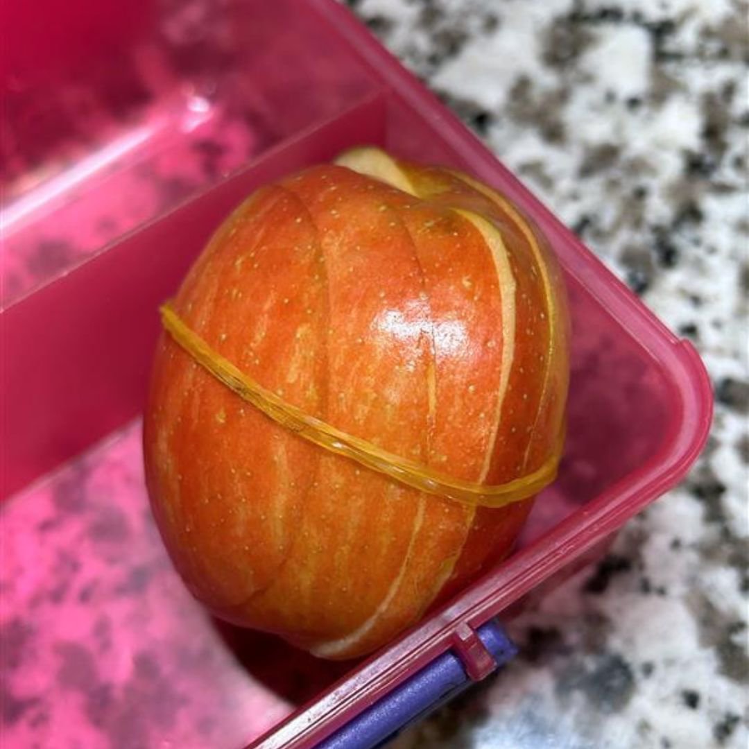 A sliced apple wrapped in a rubber band to prevent browning