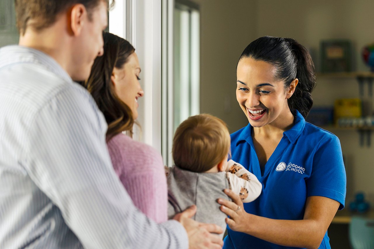 Teacher welcoming a family into the Goddard School
