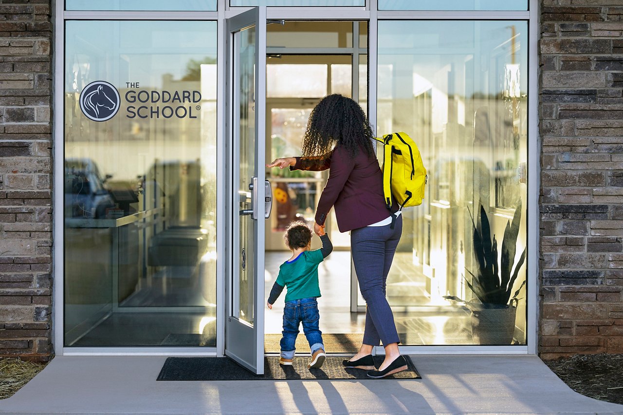 Parent walking into a Goddard School with their child