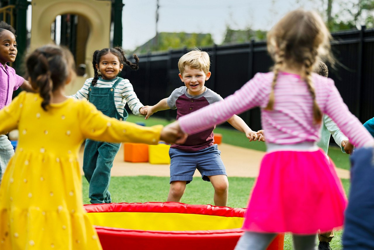 Children holding hands and spinning in a circle on a preschool playground