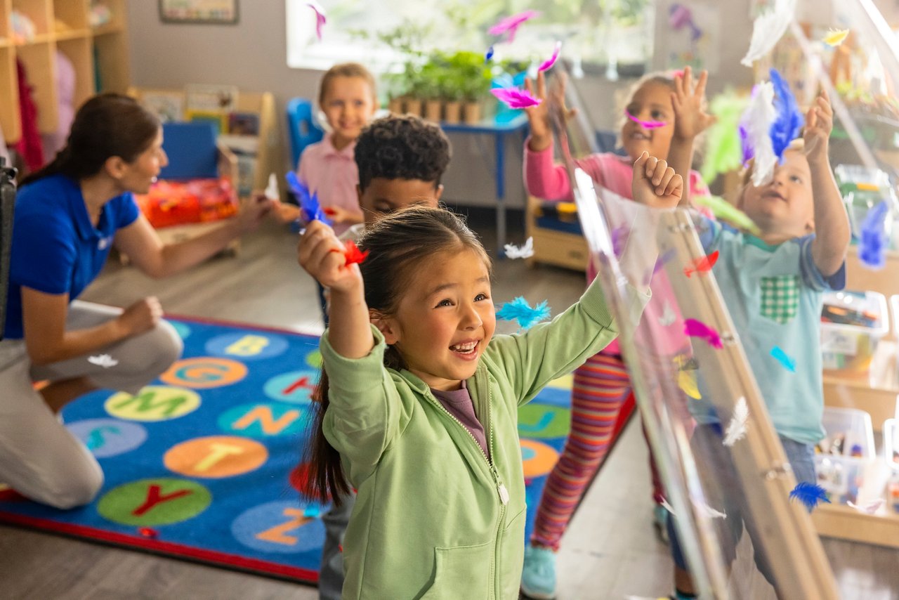 Children playing with colorful feathers in a preschool classroom