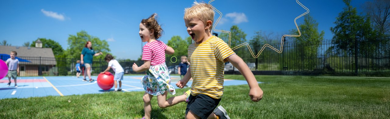 Children running across the grass on a preschool playground