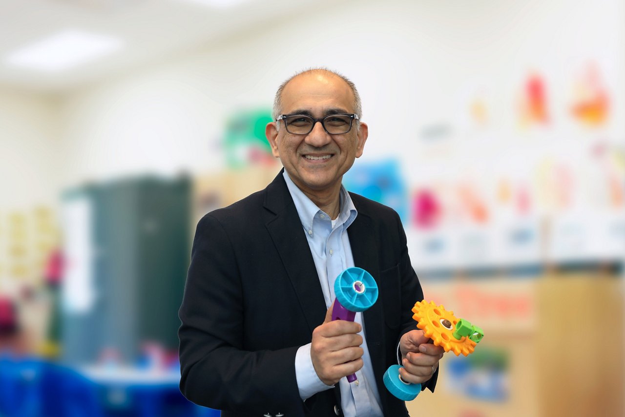 Dr. Ali Tafreshi, SVP, Chief Information Officer in classroom holding colorful toys