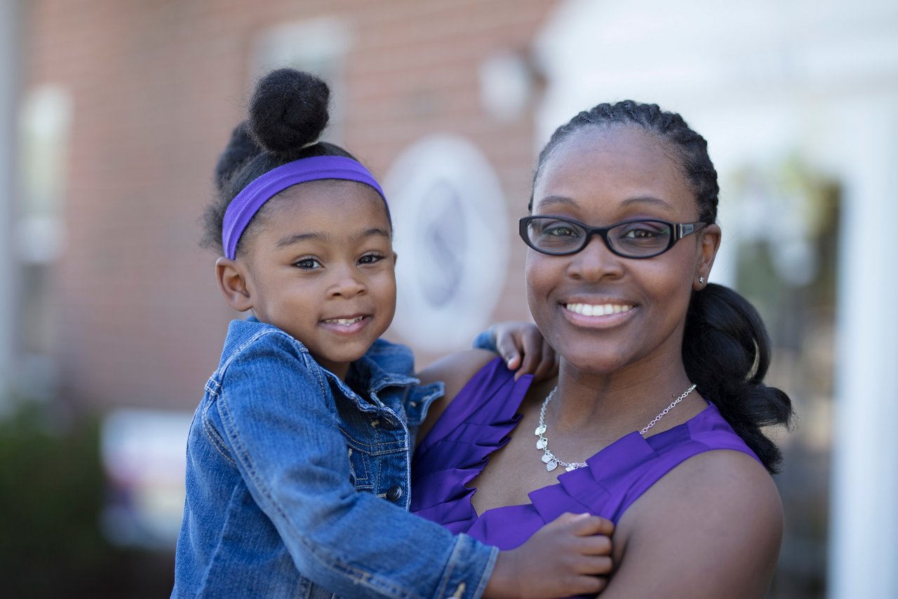 Mom holding daughter smiling outside Goddard School