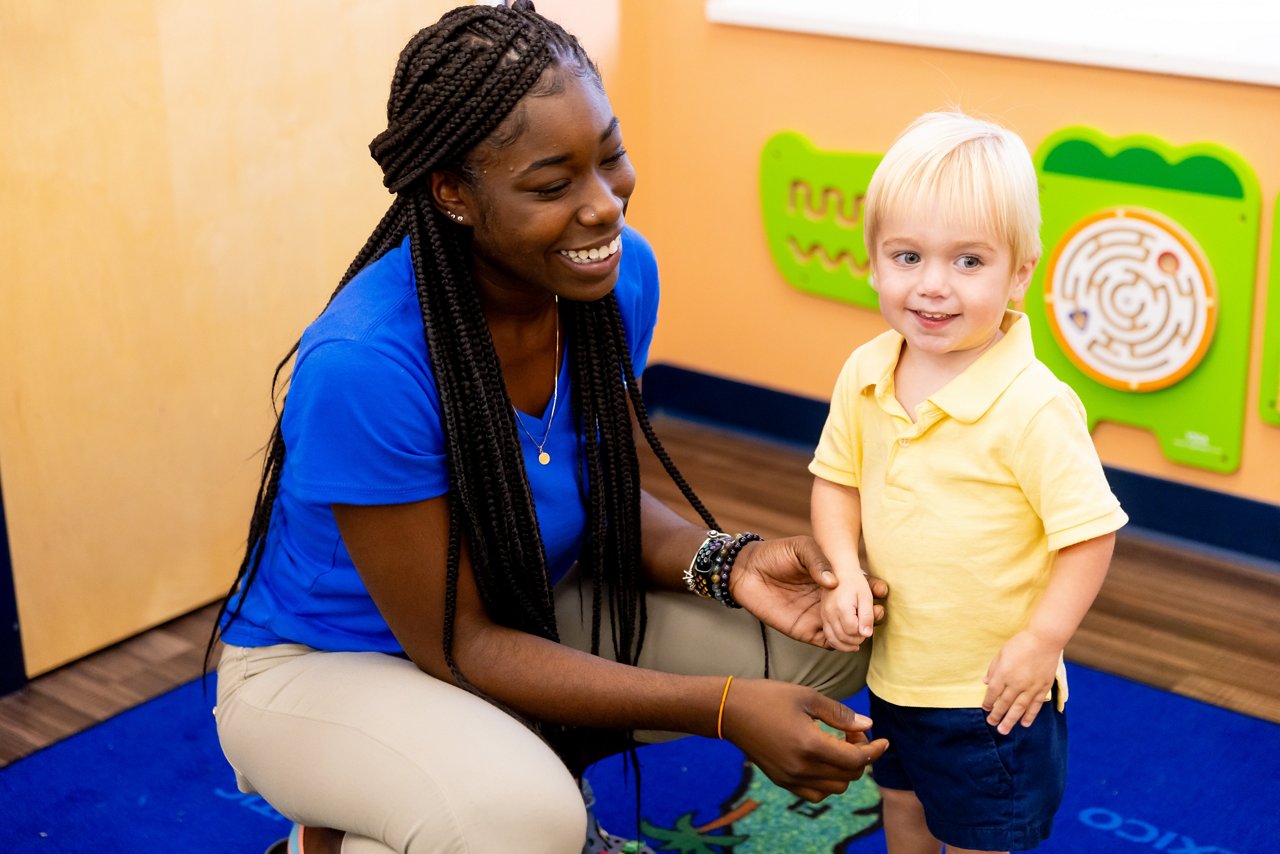 Teacher crouching down with student in a preschool classroom