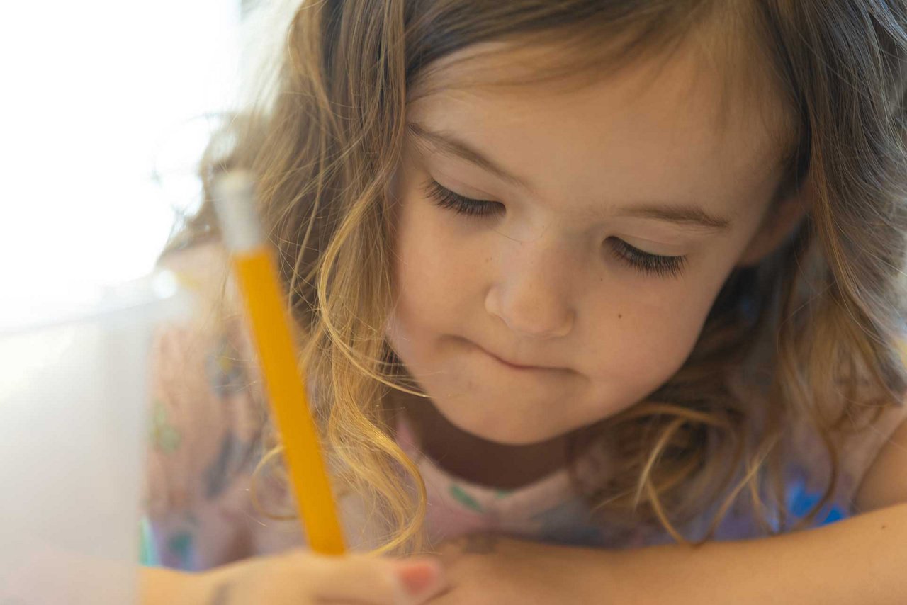 Young girl concentrating on writing with a pencil