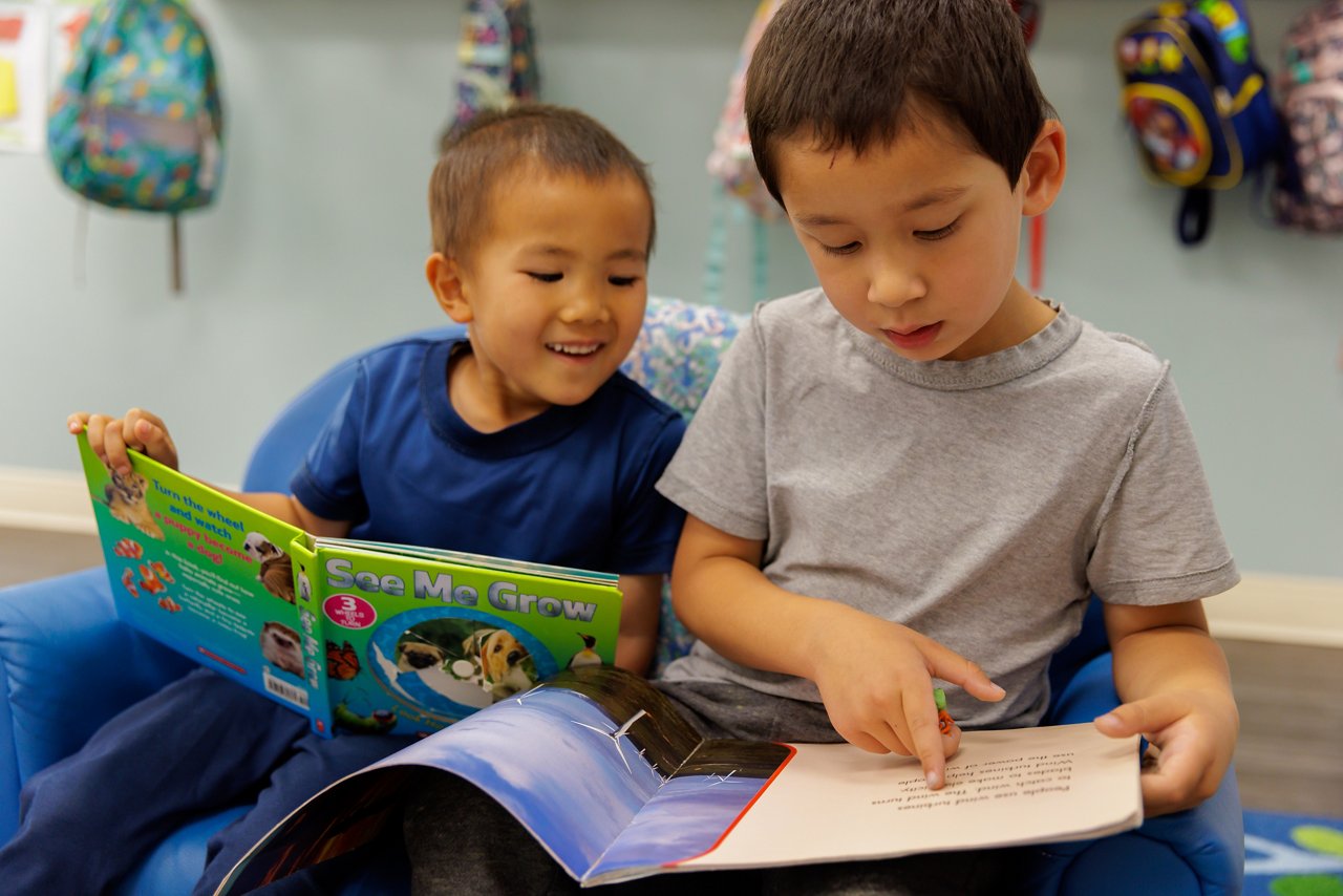two boys at a table reading a book
