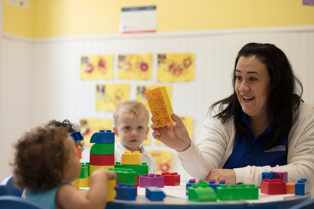 Goddard teacher playing blocks with two infant children