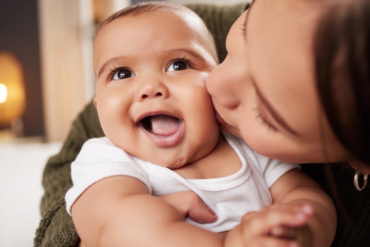 mom kissing a smiling baby on the cheek