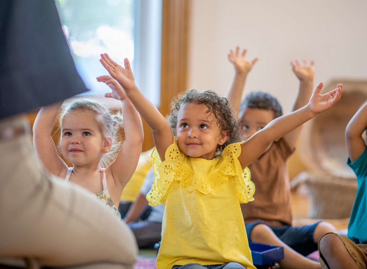 Group of diverse children in the classroom stretching and doing yoga and listening to the teacher.