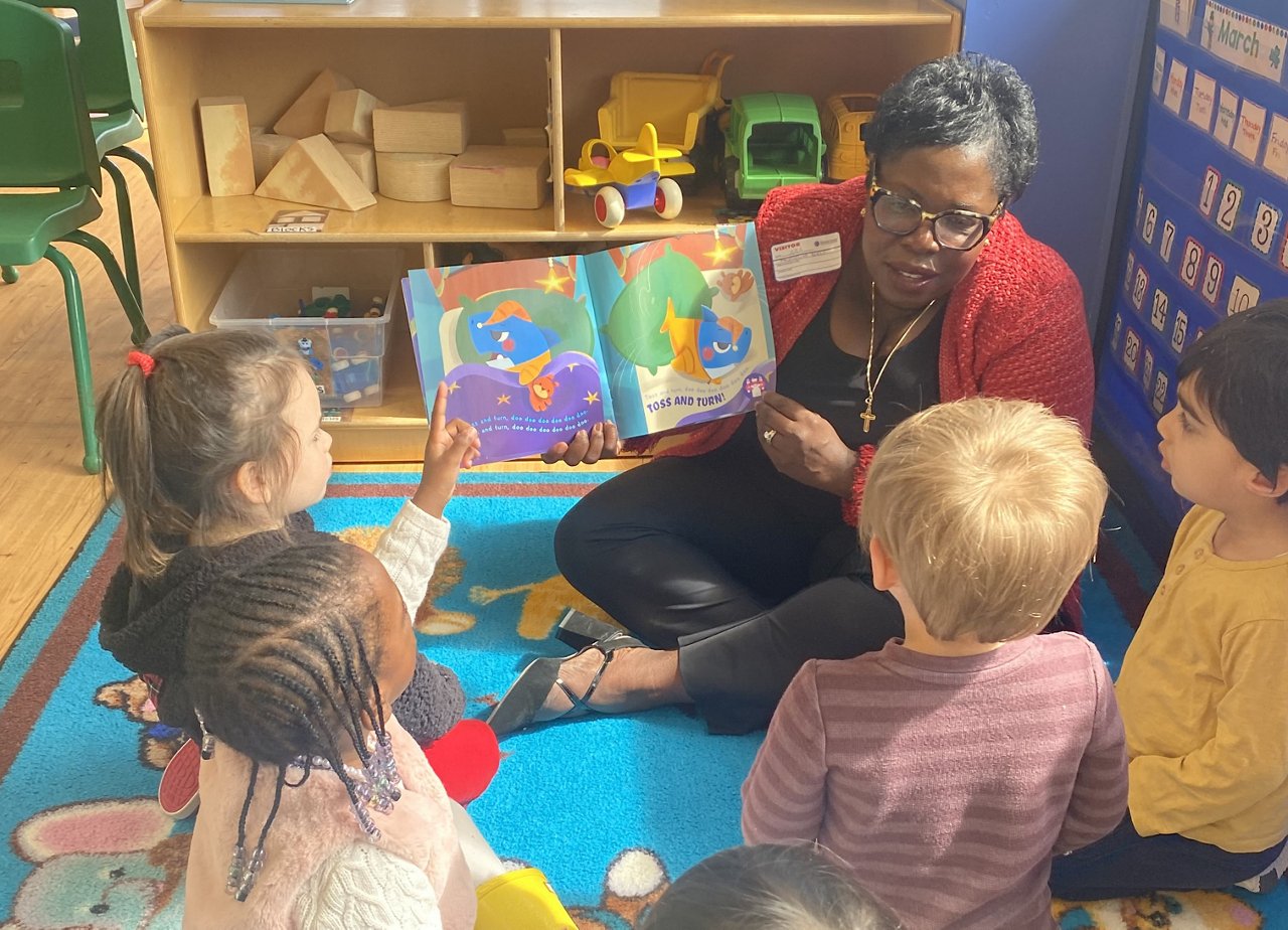 A Goddard School leadership member reading a book to children at a Goddard School
