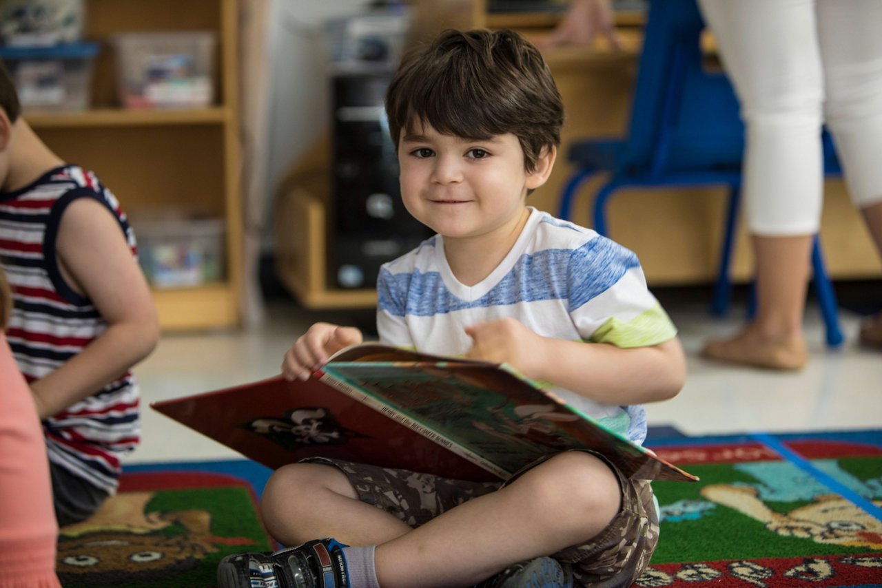 A young boy sitting on the floor reading a book