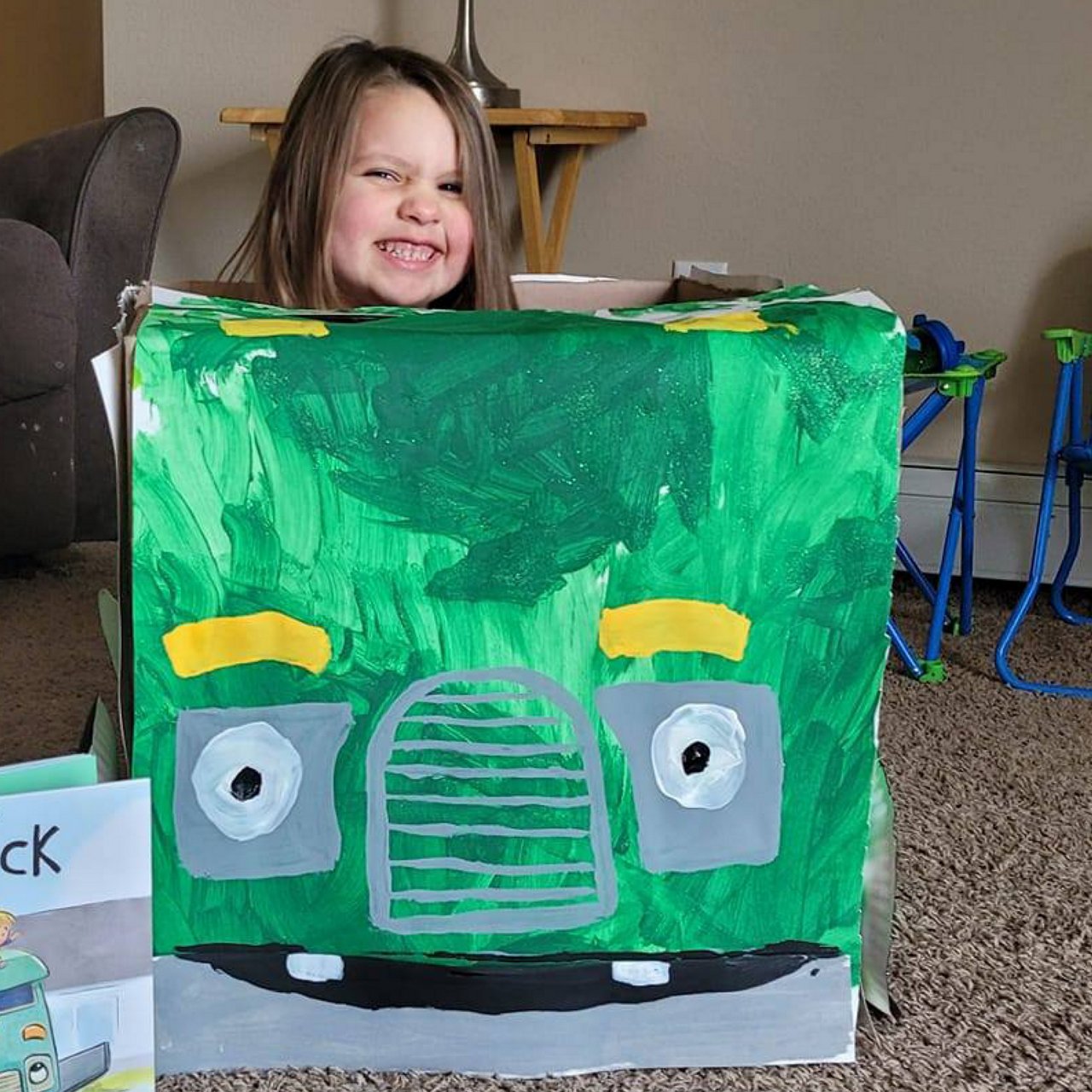Young girl smiling inside a truck made out of cardboard