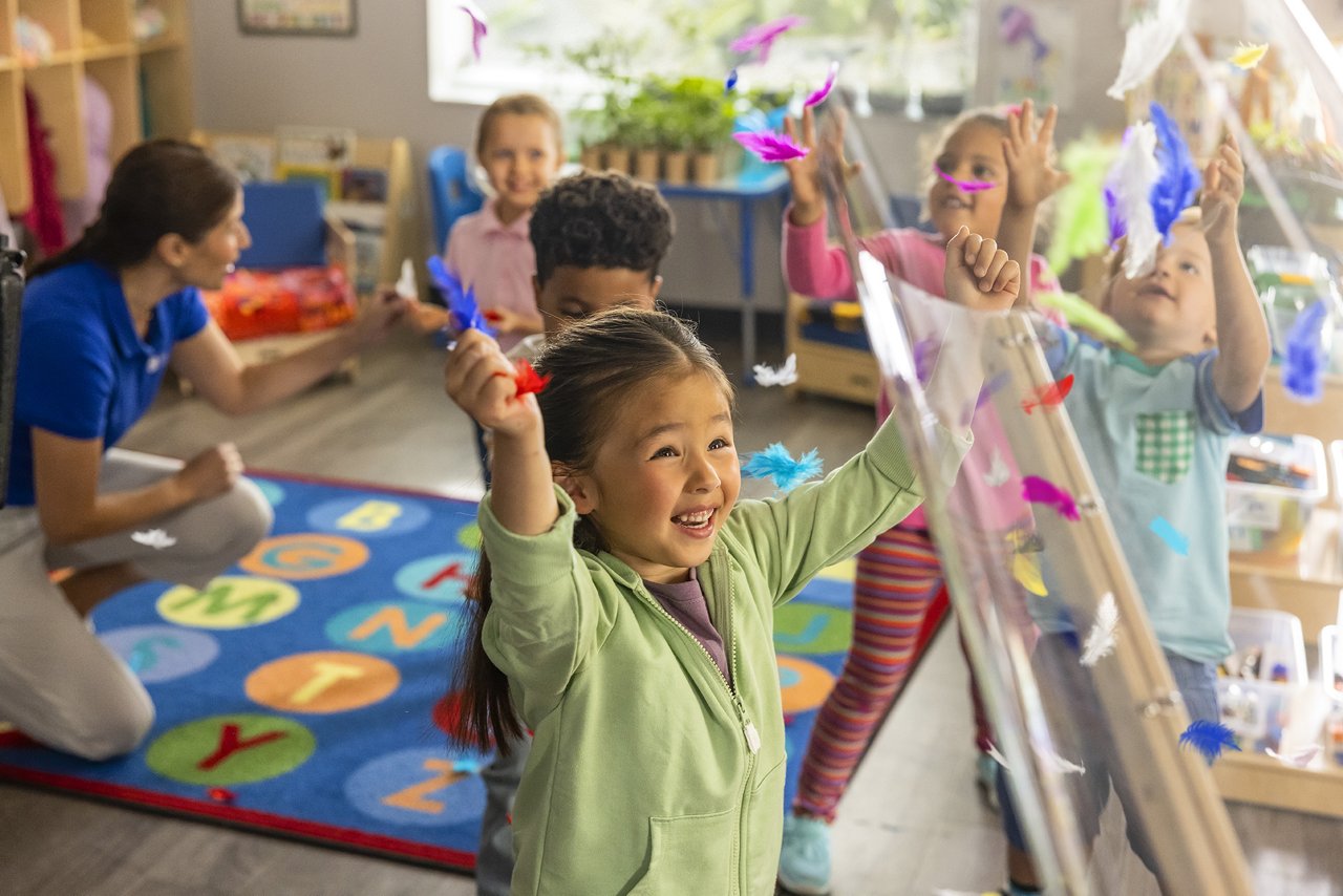 Children playing with colorful feathers in a preschool classroom