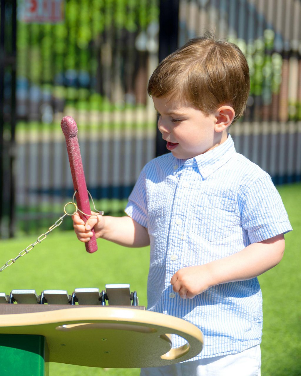 A child playing a xylophone in an outdoor classroom