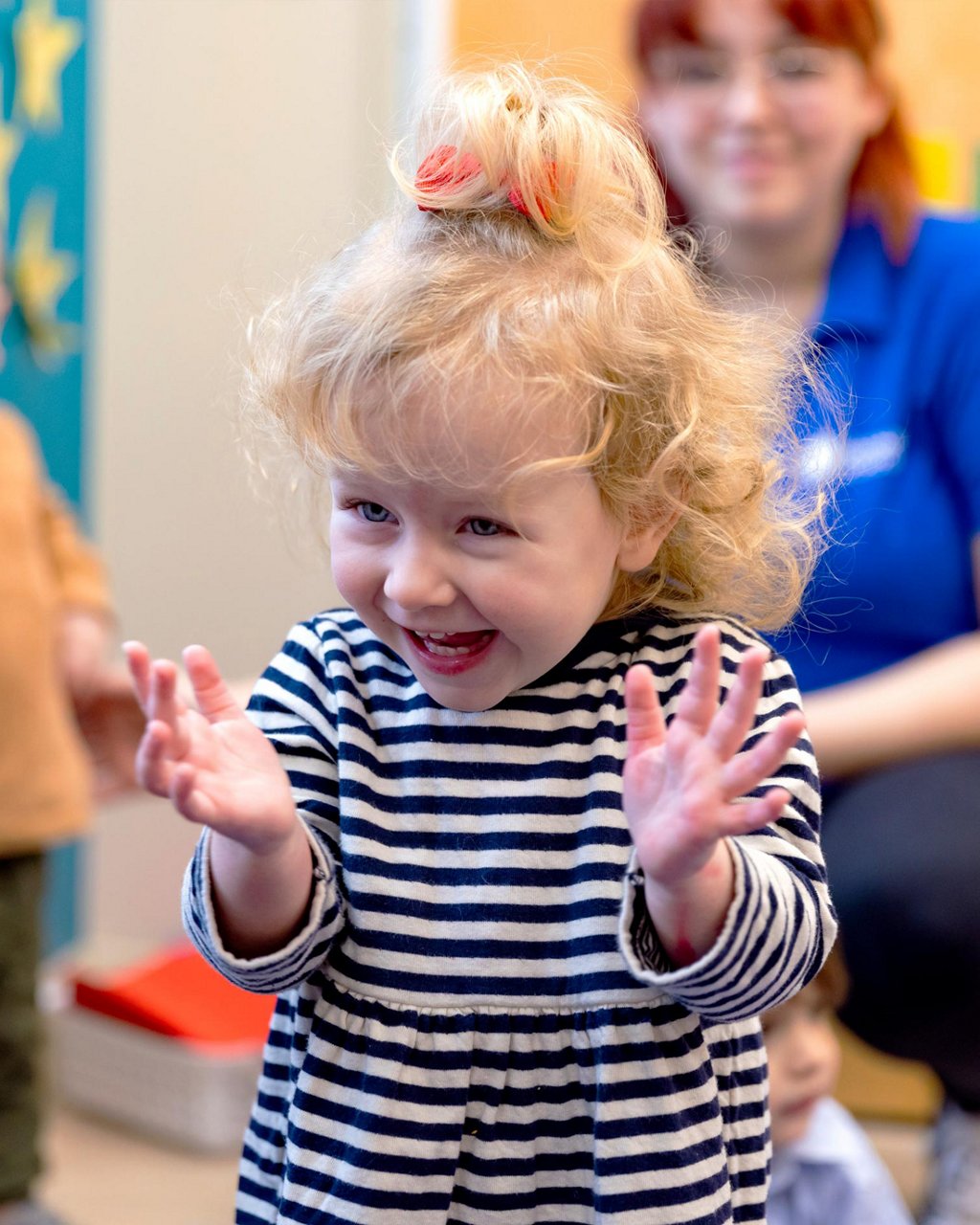 A smiling child clapping their hands 