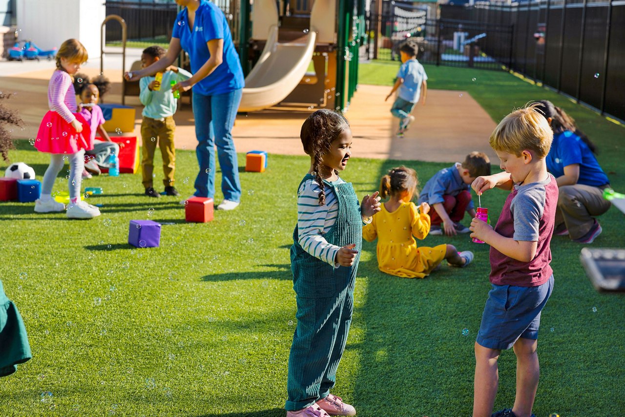 Cildren playing with bubbles on a sunny Goddard preschool playground