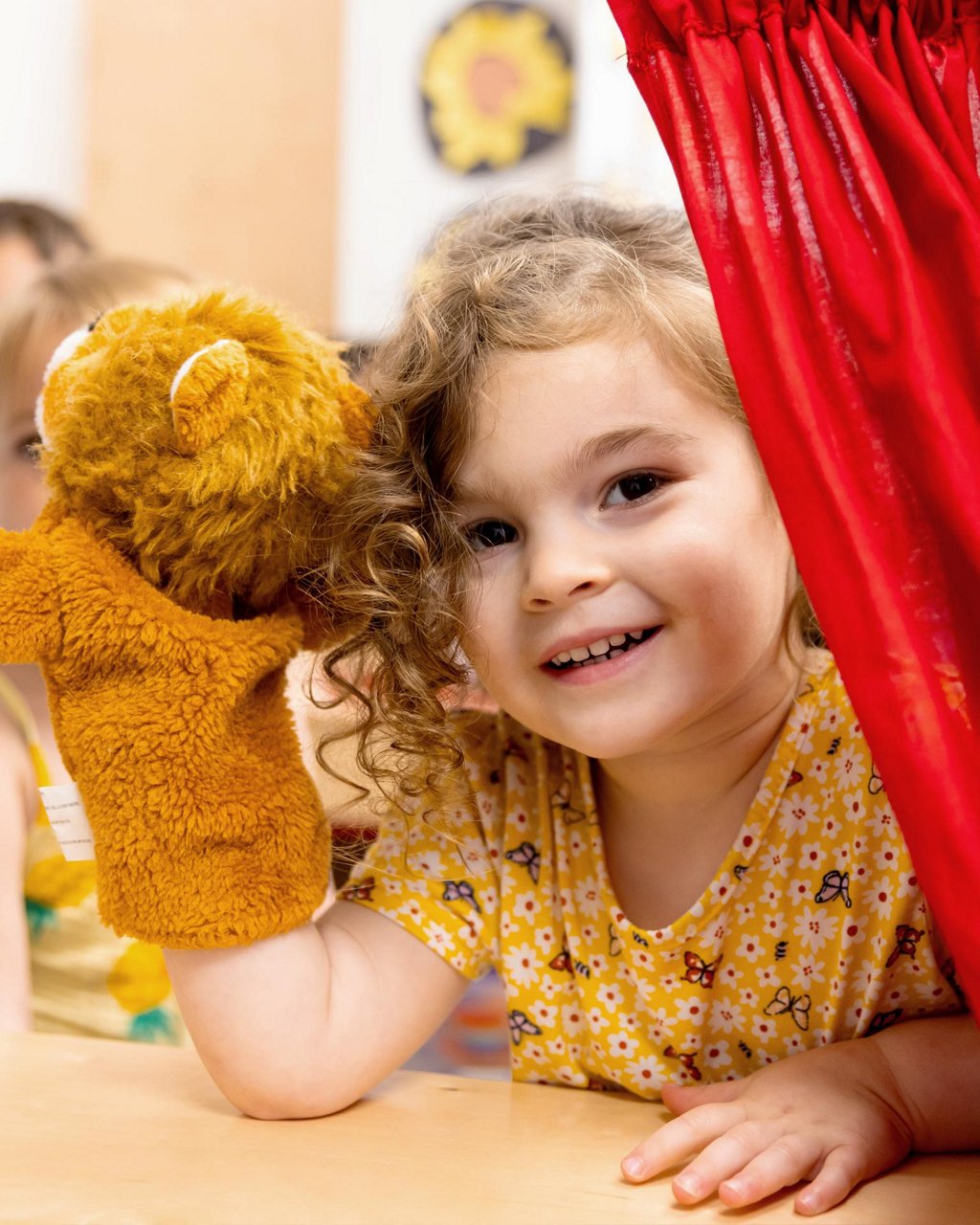 Child smiling while playing with a puppet