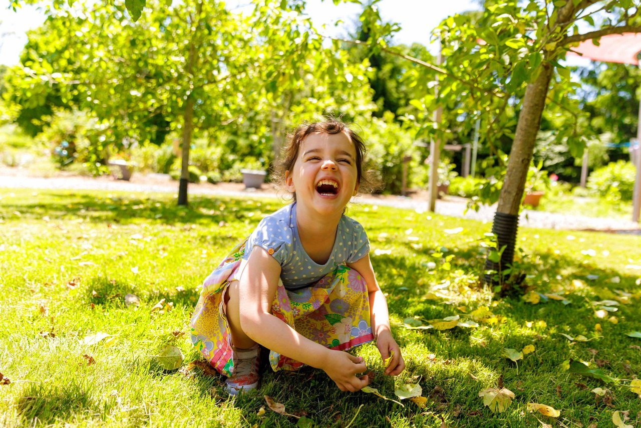 Happy girl playing outside in the sunshine at a Goddard preschool