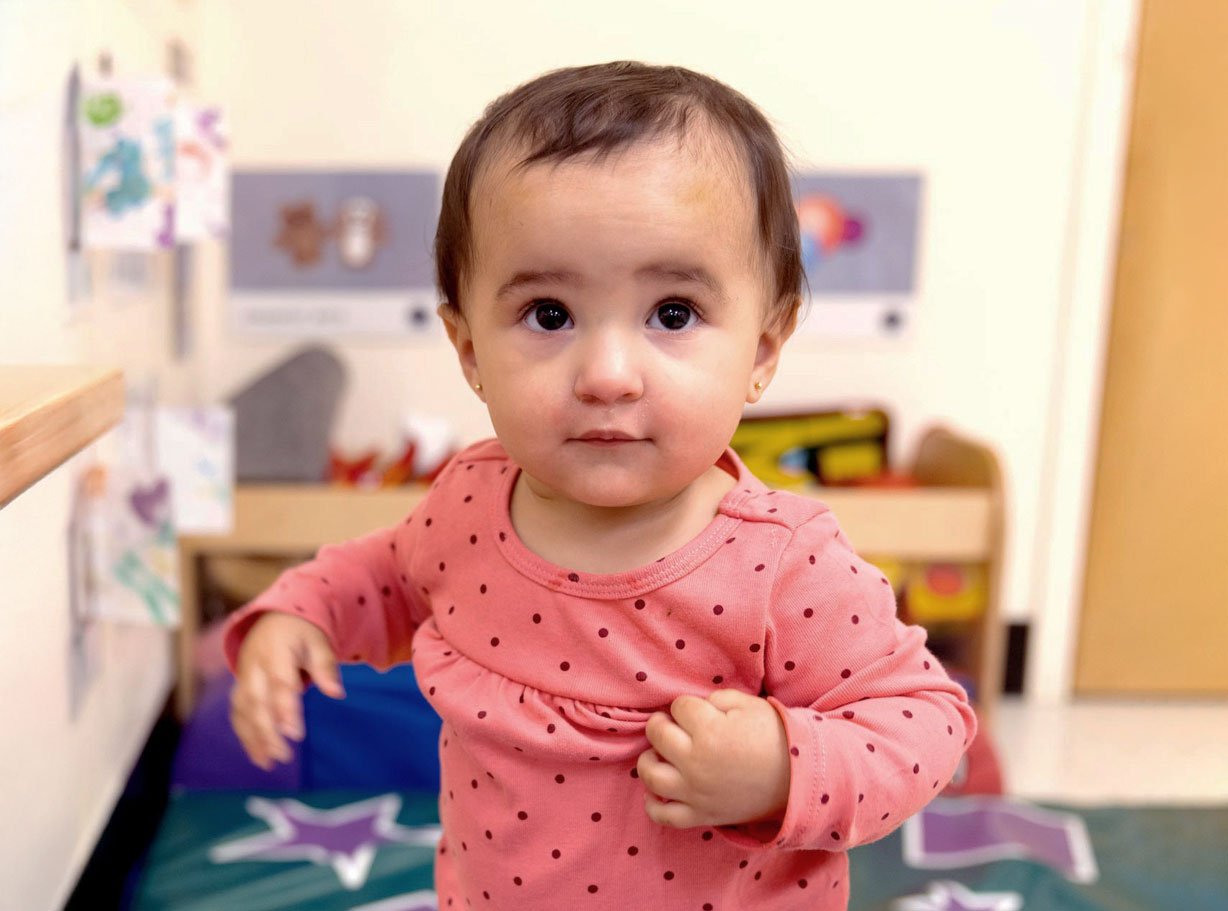 Preschool child standing in a colorful classroom with artwork, toys, and learning materials, highlighting a creative and engaging early childhood environment.