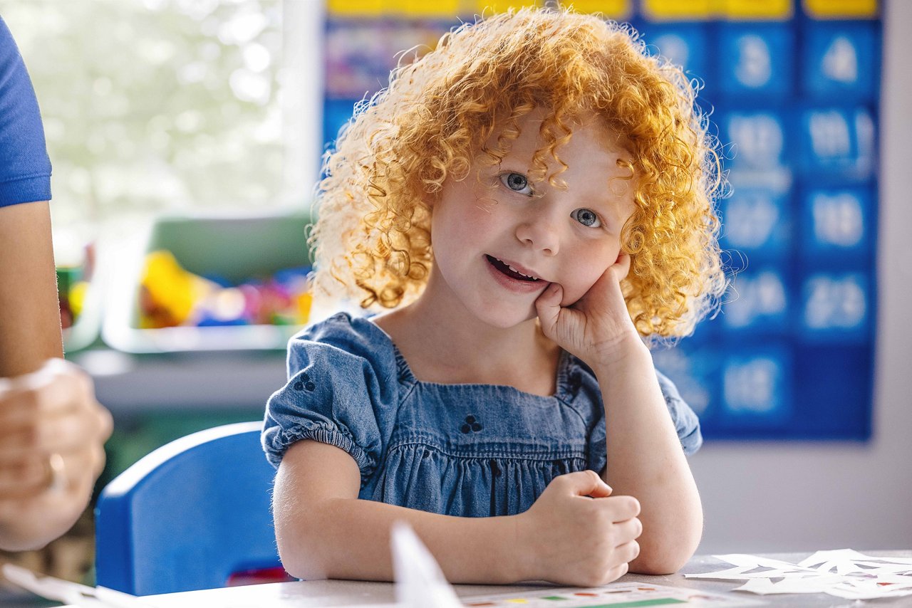 Little girl sitting at a desk in a Goddard preschool