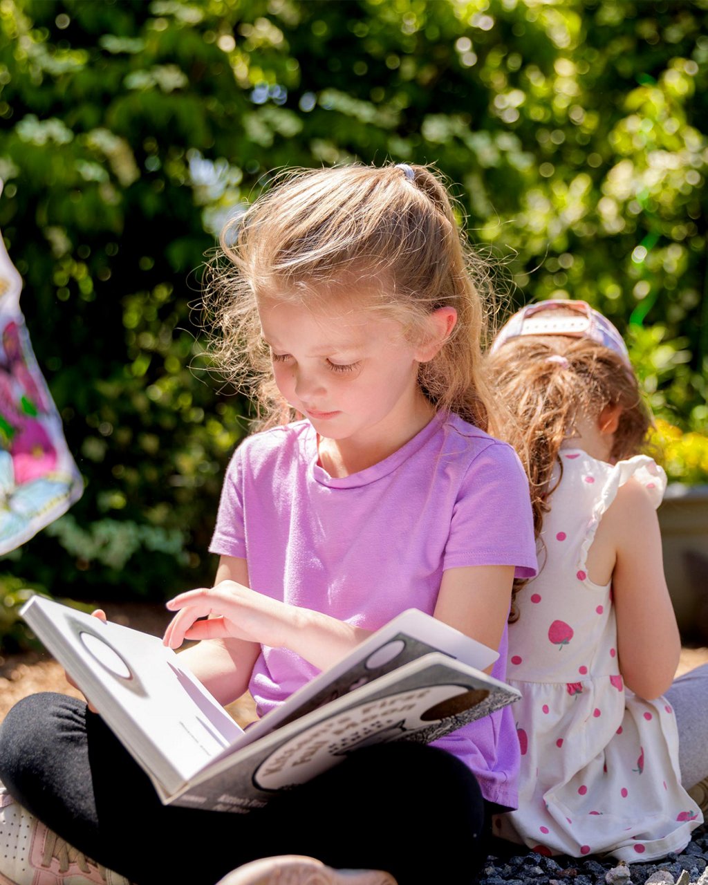 A child reading a book outdoors 