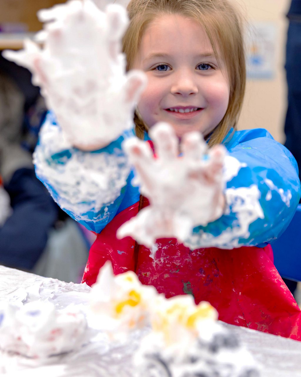 A child showing their foam-covered hands to the camera