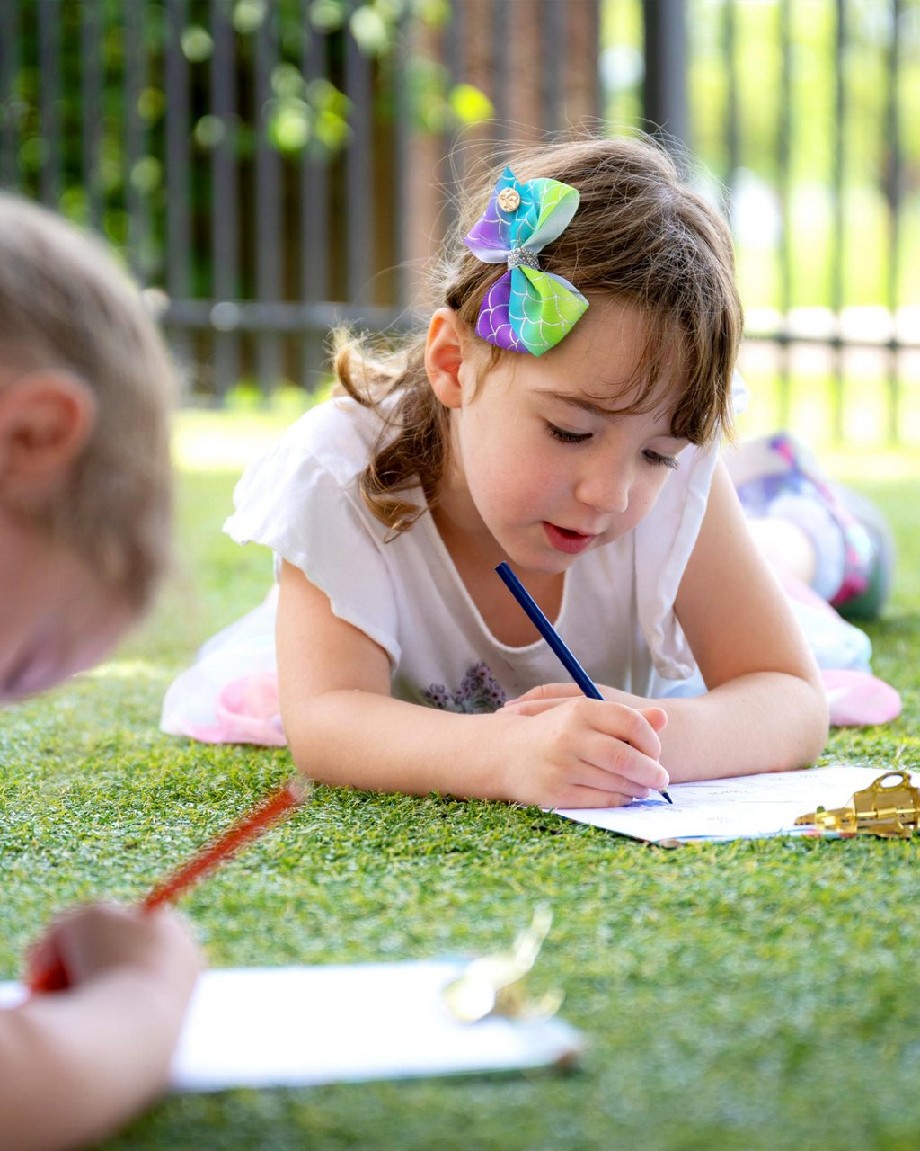 A child lying on the ground writing with a pencil 