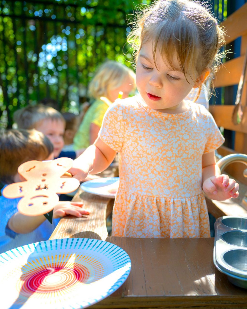 A child playing with a gingerbread cutout in an outdoor classroom