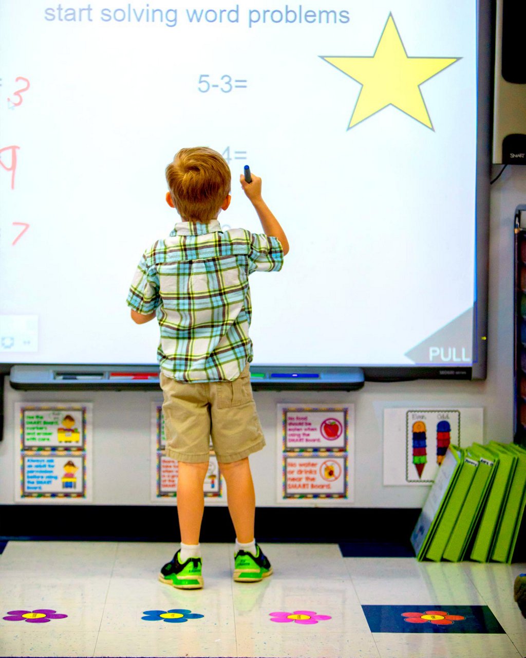 A child solving math problems at a smart board 