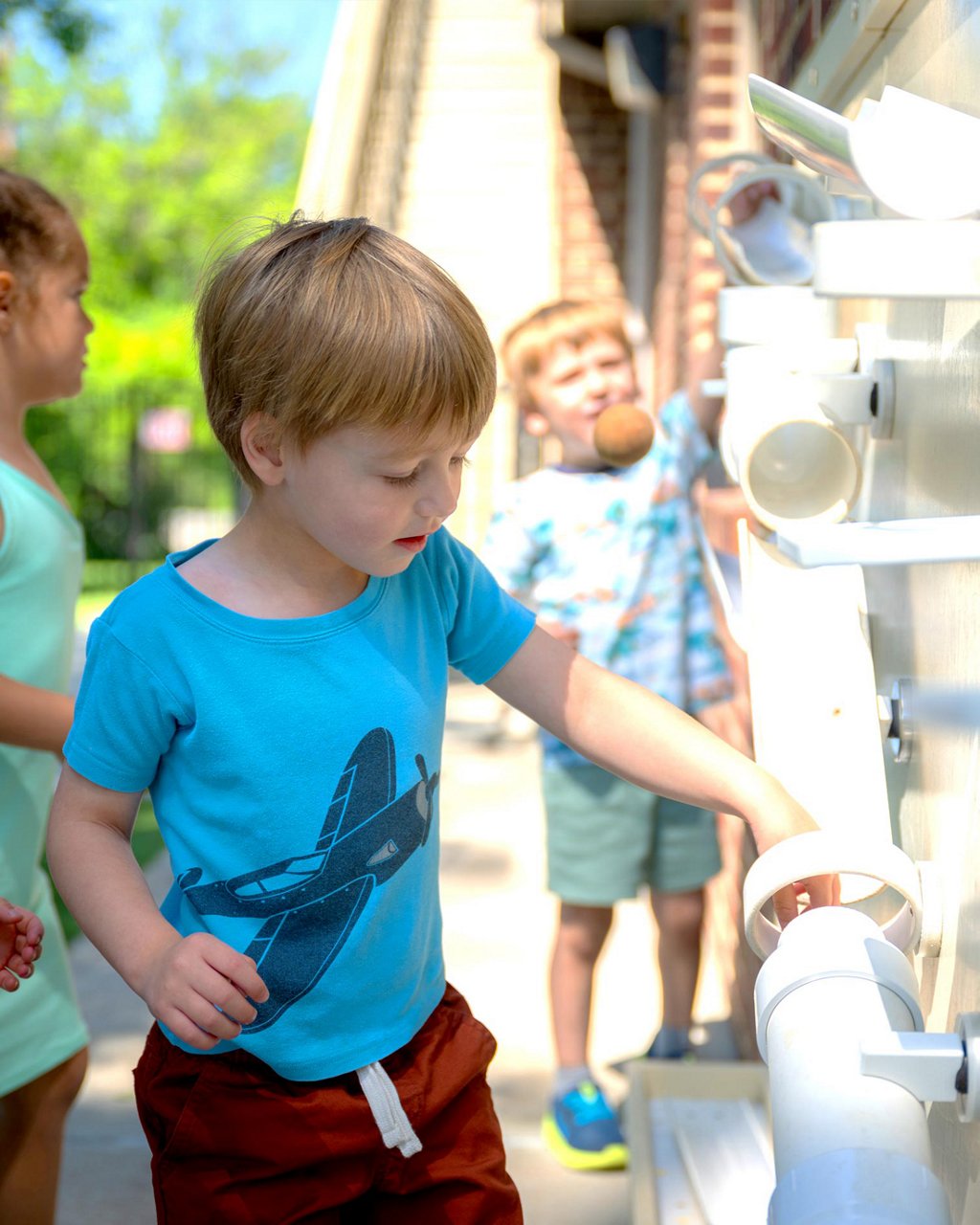 A child dropping a ball into a pipe maze 